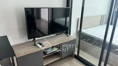 Modern bedroom with TV and sliding glass doors, featuring sleek wooden furniture.