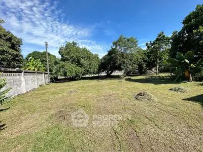 Spacious green land plot with lush trees and clear blue sky, perfect for development opportunities.