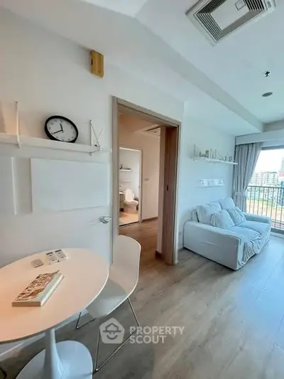 Modern living room with cozy seating and balcony view in a stylish apartment.