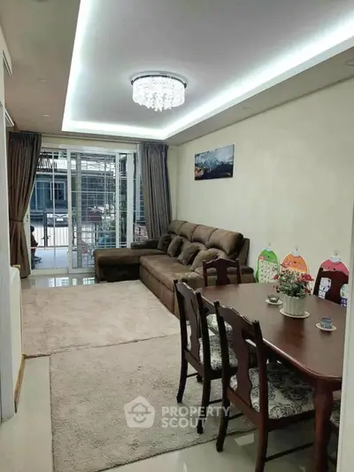Elegant living room with plush sofa and dining area, featuring modern lighting and balcony access.