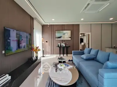 Modern living room with sleek design and blue sofa, featuring a wall-mounted TV and stylish decor.