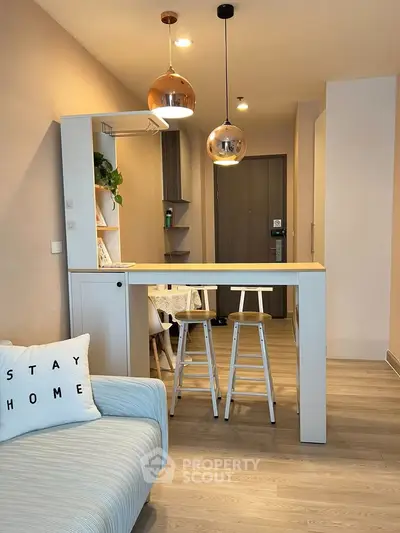 Modern living room with stylish decor and cozy seating area, featuring pendant lights and a breakfast bar.