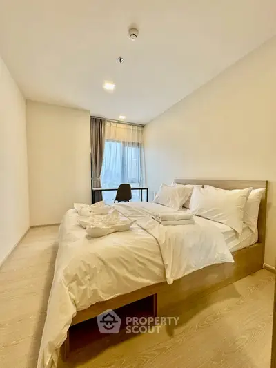 Spacious bedroom with modern decor and large window offering city views.