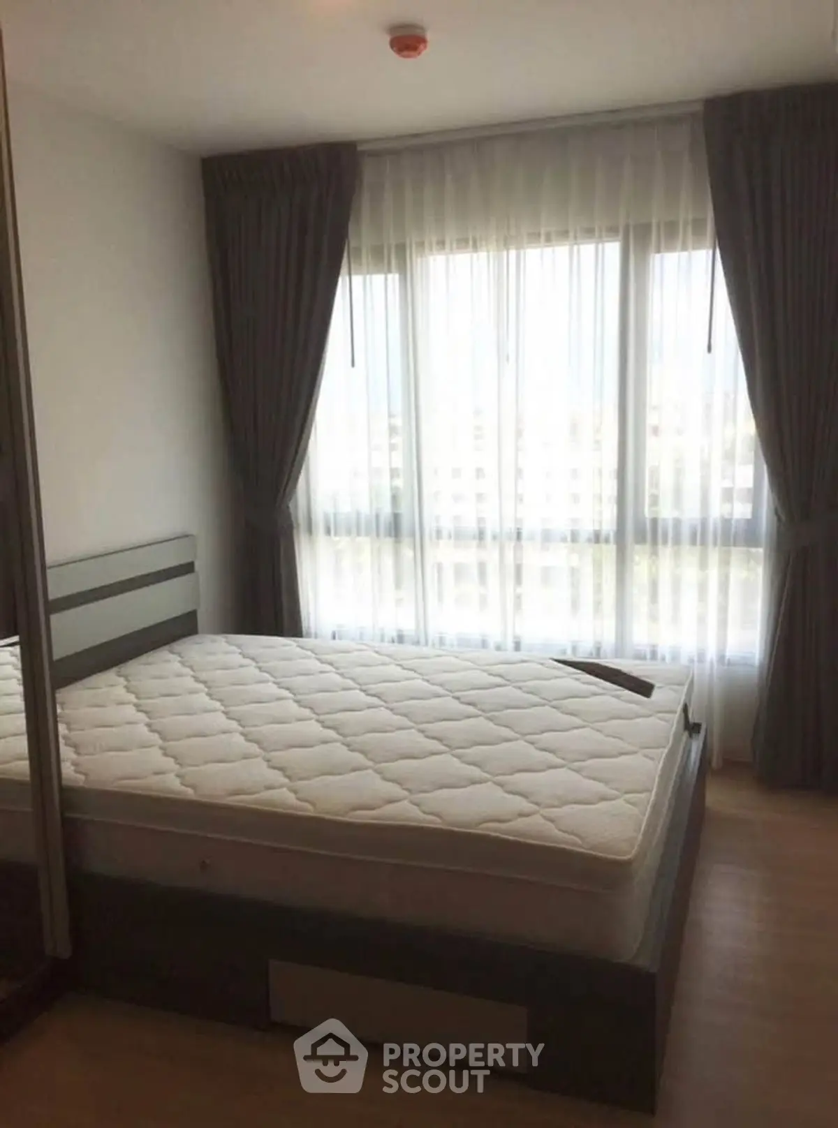 Cozy bedroom with large window and elegant curtains, perfect for natural light lovers.