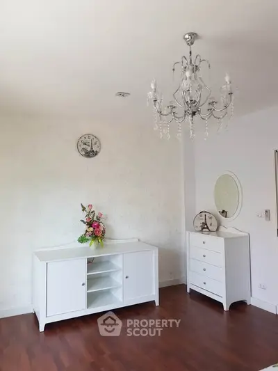 Elegant living room with chandelier and stylish white furniture on wooden floor