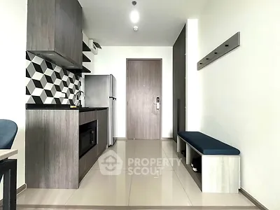 Modern kitchen with sleek cabinetry and stylish backsplash in a compact apartment setting.