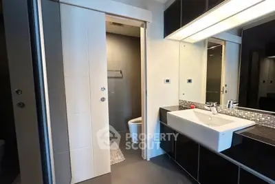 Modern bathroom with sleek design, featuring a large mirror, stylish sink, and contemporary fixtures.