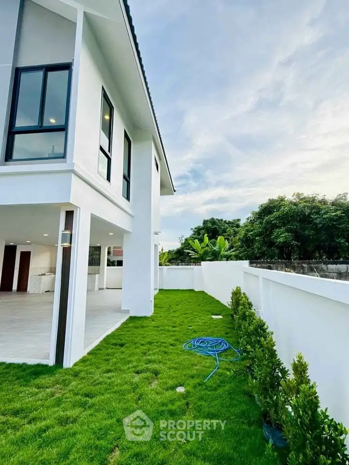 Modern two-story house with lush green lawn and spacious outdoor area, perfect for family living.