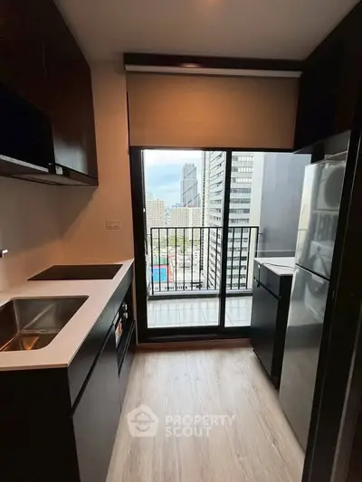 Modern kitchen with sleek cabinetry and balcony view in urban high-rise apartment.