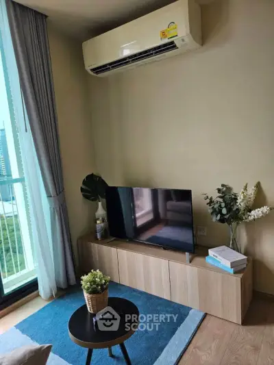 Modern living room with air conditioning and stylish decor, featuring a TV and natural light from large windows.