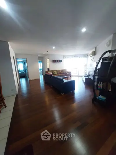 Spacious living room with wooden flooring and modern furniture, ideal for family gatherings.