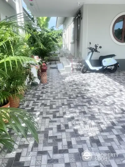 Charming outdoor patio with stylish tiles and lush greenery, perfect for relaxation and leisure.