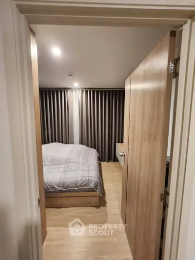 Cozy bedroom with wooden flooring and modern decor, featuring a comfortable bed and stylish curtains.
