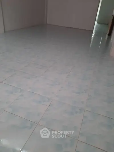 Spacious empty room with tiled flooring, ready for customization.