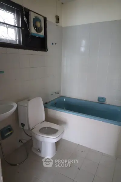 Cozy bathroom with blue bathtub and white tiles, ideal for relaxation.