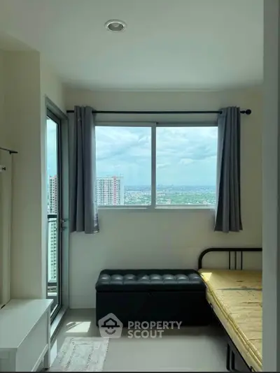 Bright bedroom with large window and city view, featuring a single bed and storage bench.