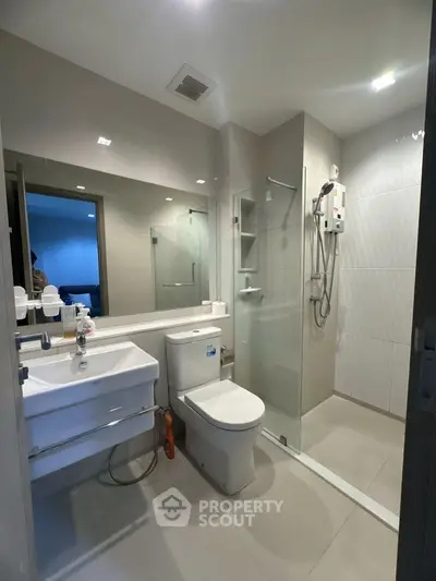 Modern bathroom with glass shower and sleek fixtures in a contemporary apartment.