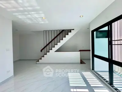Modern minimalist living room with sleek staircase and large windows