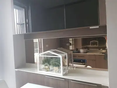 Modern kitchen with sleek cabinetry and built-in oven, featuring stylish decor.