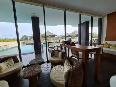 Luxurious living room with pool view and modern furnishings in a serene setting.