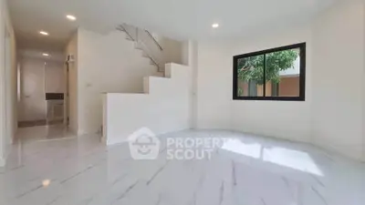 Spacious modern living room with large window and elegant staircase
