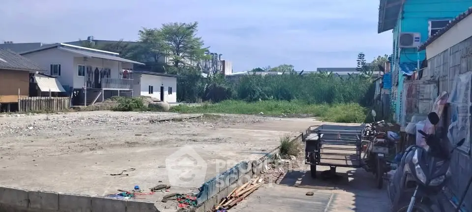 Vacant land plot with potential for development in a residential area, featuring nearby houses and open space.