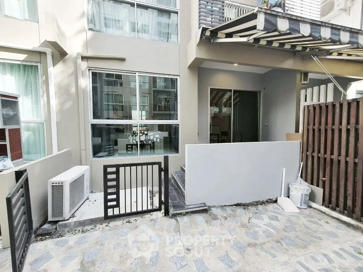 Modern townhouse exterior with large windows and small gated entrance