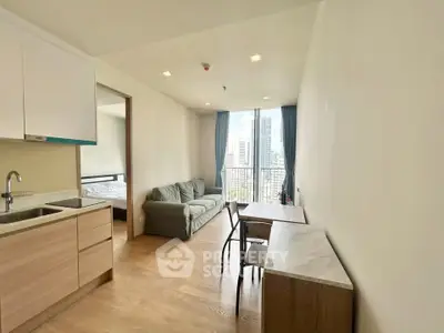 Modern apartment interior with open living room and kitchen, featuring city view from balcony.