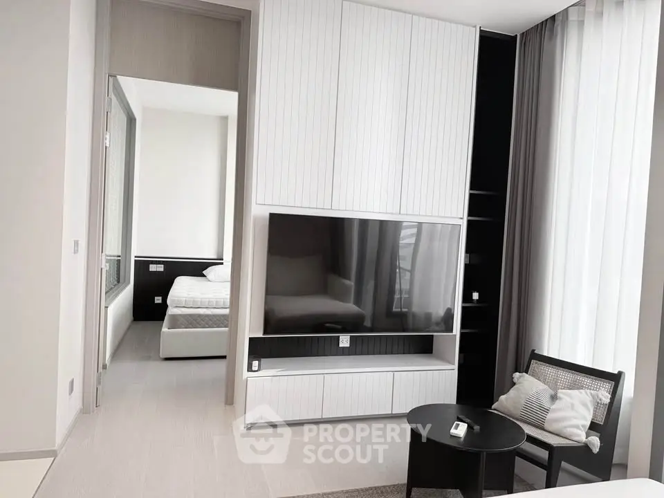 Modern living room with sleek TV unit and view into a stylish bedroom