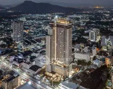 Stunning aerial view of illuminated high-rise building in vibrant cityscape at dusk.