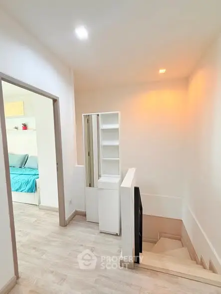 Modern interior with wooden flooring and staircase leading to a cozy bedroom.