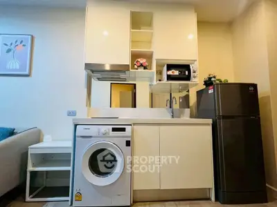 Modern kitchen with washing machine and fridge in compact apartment