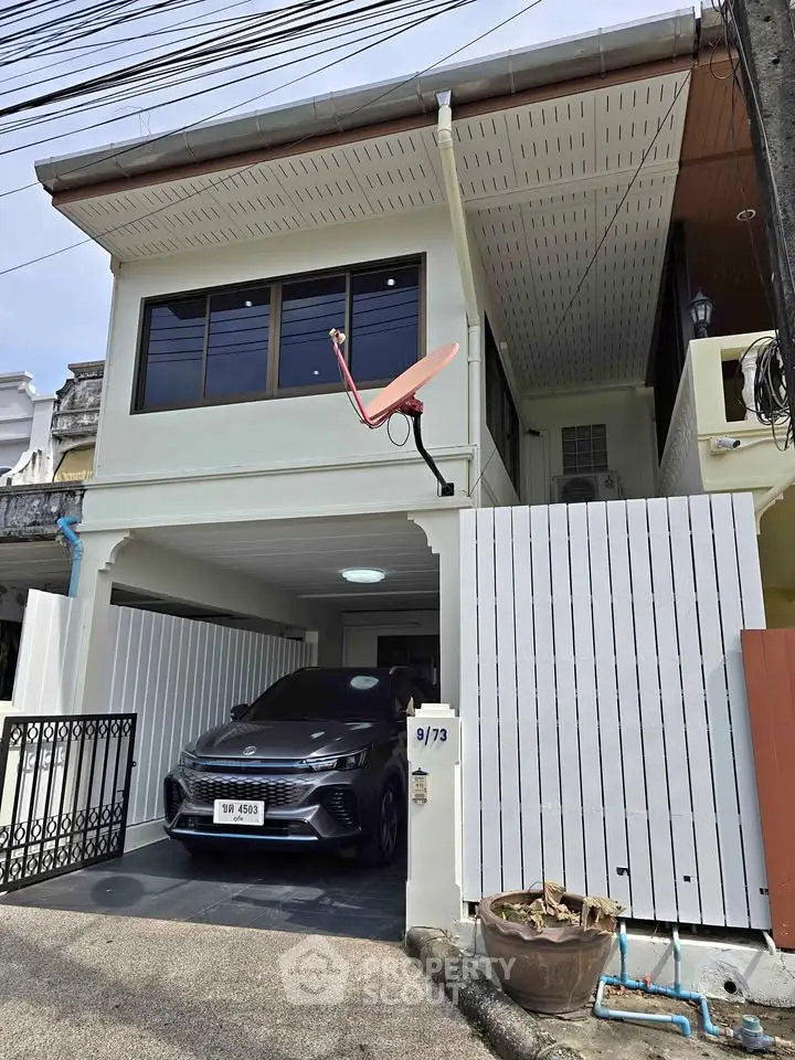 Charming two-story house with carport and satellite dish in a quiet neighborhood.