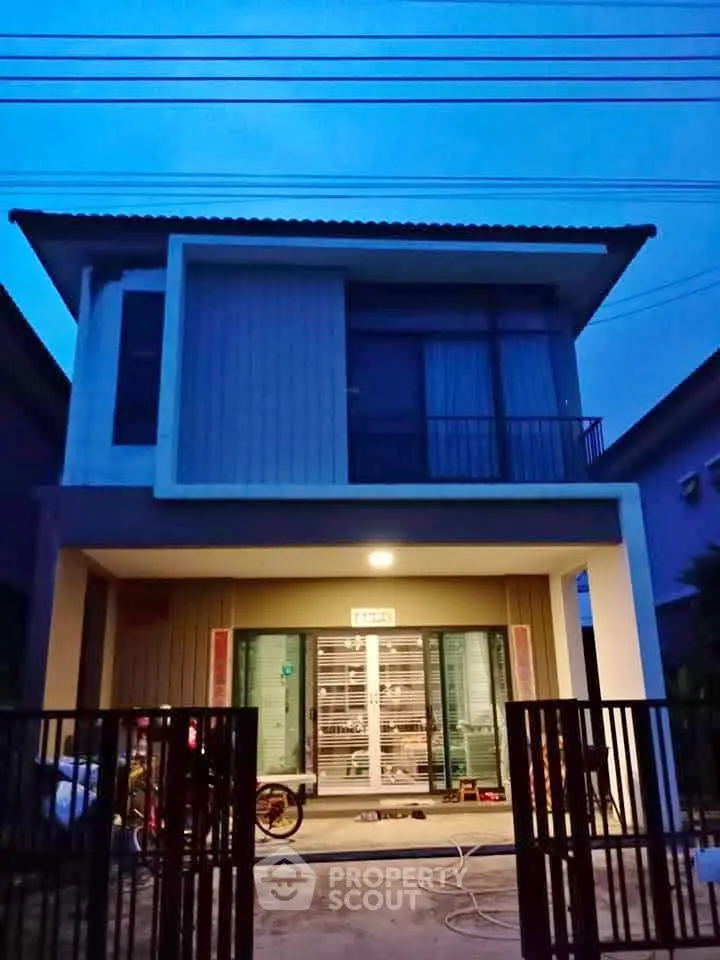 Modern two-story house with a sleek facade and warm lighting at dusk.