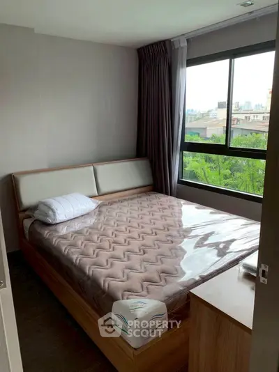 Cozy bedroom with large window offering lush green view, featuring a comfortable bed and modern decor.