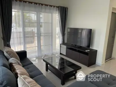 Modern living room with large TV and stylish furniture, perfect for relaxation and entertainment.