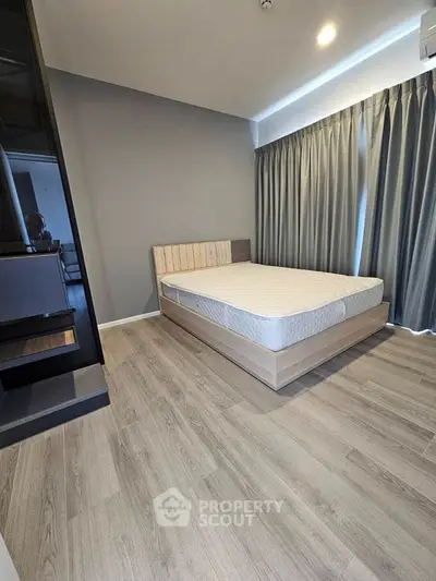 Modern bedroom with sleek design and large window, featuring a comfortable bed and stylish flooring.