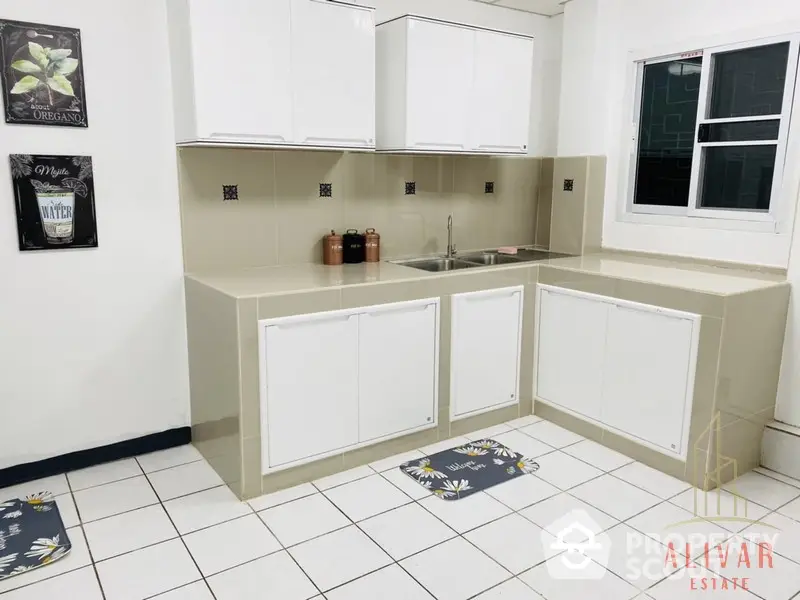 Compact kitchen space with white cabinetry and tiled flooring, ideal for efficient cooking in a cozy home environment.