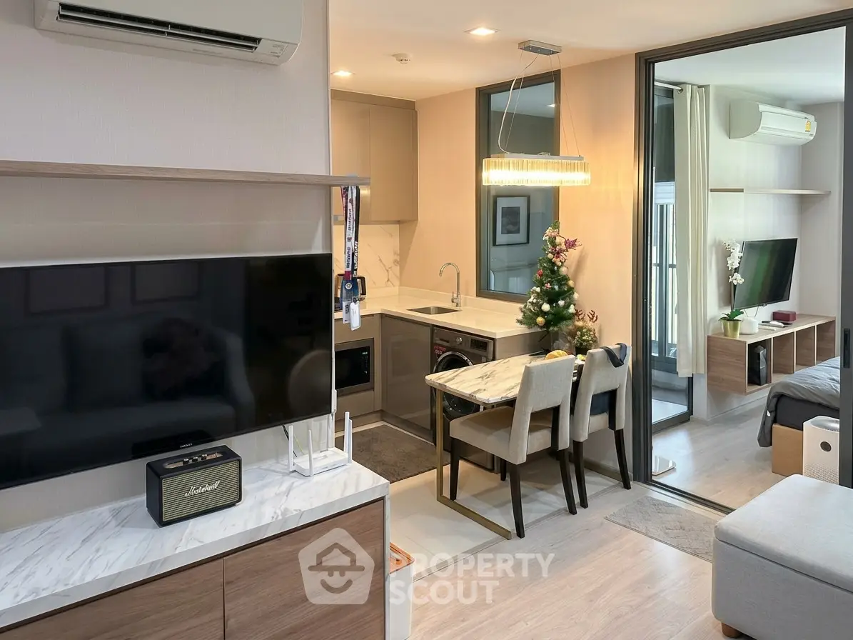 Modern open-plan living room with stylish kitchen and dining area, featuring sleek furniture and contemporary decor.
