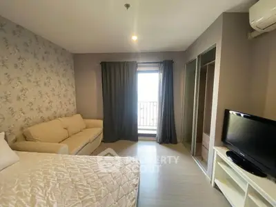 Cozy bedroom with modern decor, featuring a comfortable bed, sofa, and flat-screen TV near a window with curtains.