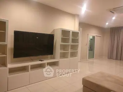 Spacious modern living room with sleek furniture and large TV, perfect for relaxation.