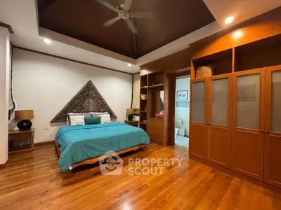 Spacious bedroom with wooden flooring and built-in wardrobe, featuring elegant decor and cozy ambiance.