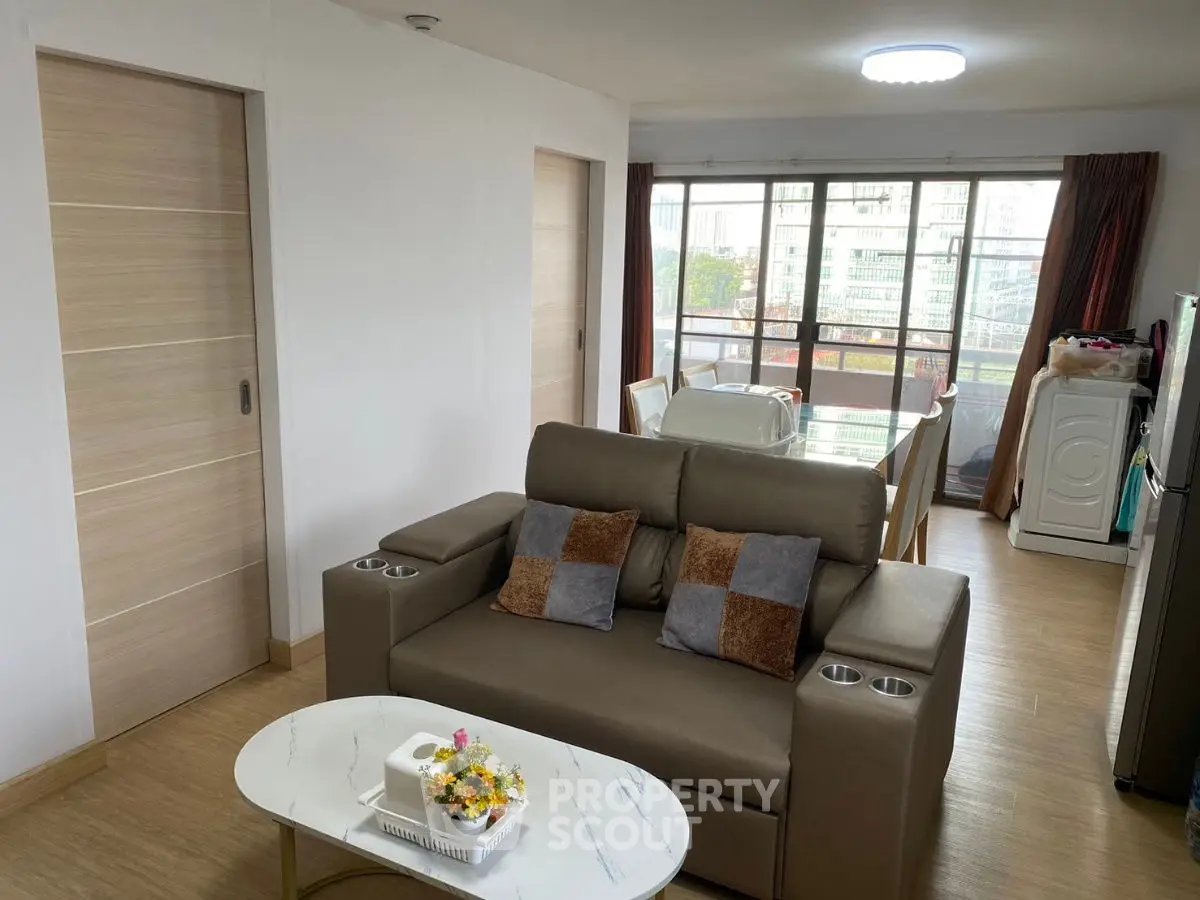 Modern living room with cozy sofa and dining area, featuring large windows and natural light.