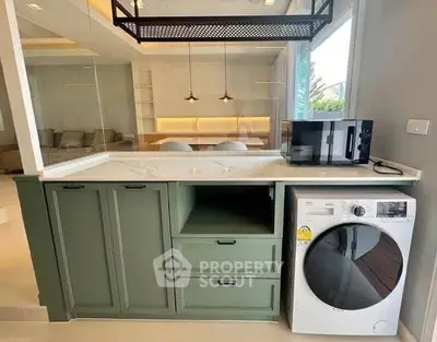 Modern kitchen with green cabinetry and built-in washing machine