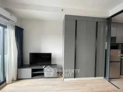 Modern living room with sleek TV stand and sliding glass door to kitchen area.