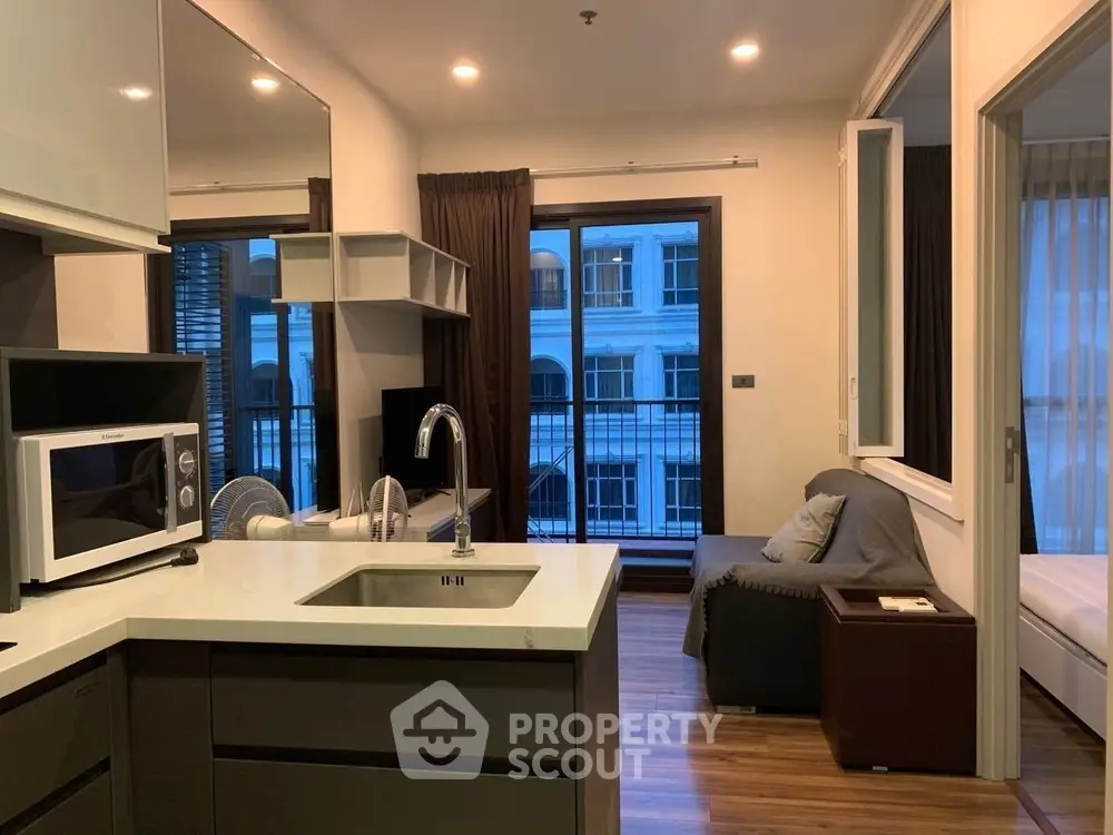 Modern open-layout apartment with sleek kitchen and cozy living area, featuring large windows and stylish decor.