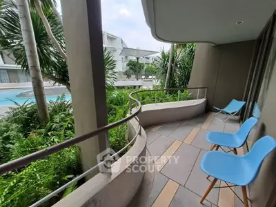 Spacious balcony with pool view and modern seating in a tropical setting.