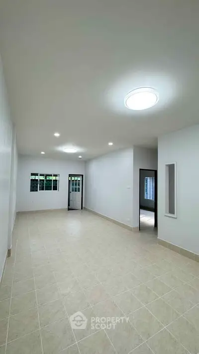 Spacious unfurnished living room with modern lighting and tiled flooring, perfect for customization.
