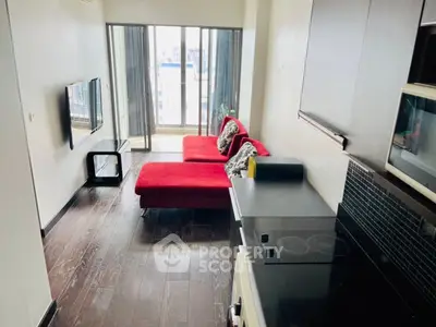 Modern apartment with sleek kitchen and cozy living area featuring a red sofa and balcony view.