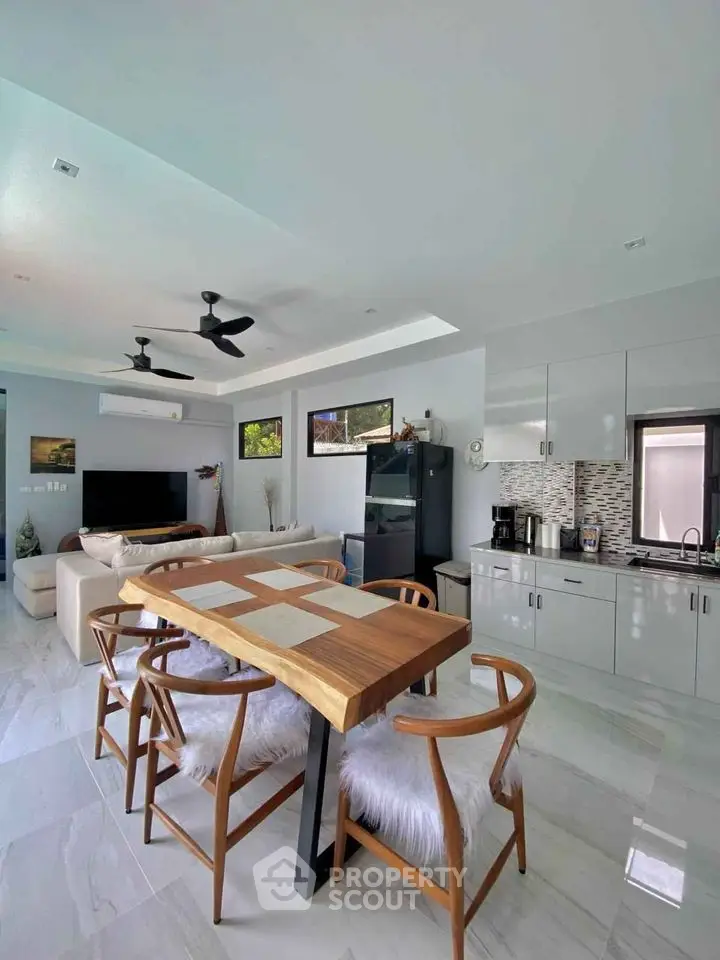 Spacious open-plan living area with modern kitchen, sleek cabinetry, and stylish dining set, perfect for entertaining and relaxation.